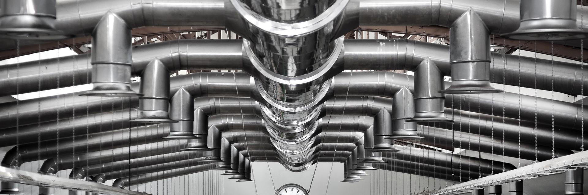 Industrial ventilation and air treatment ductwork suspended from the ceiling of a manufacturing facility