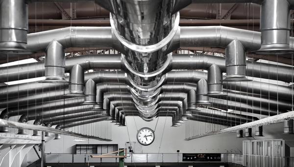 Industrial ventilation and air treatment ductwork suspended from the ceiling of a manufacturing facility