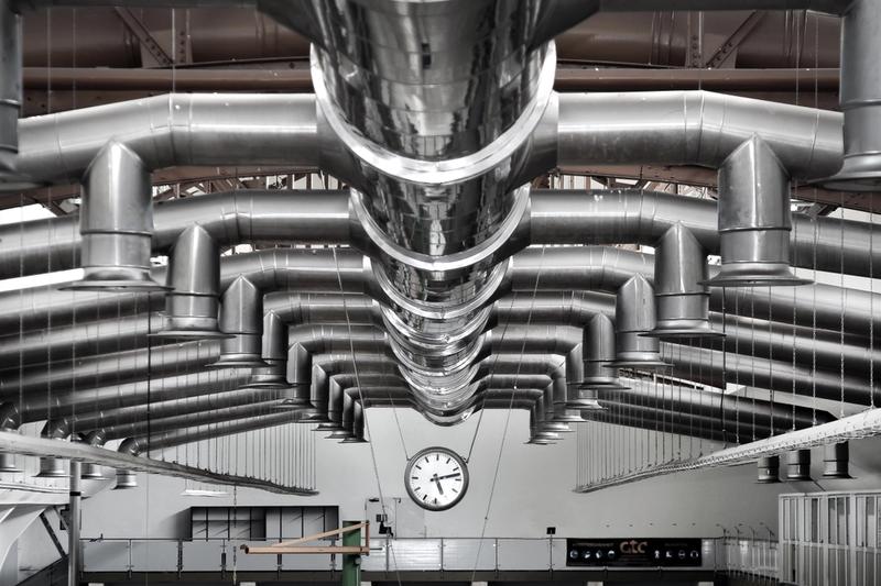 Industrial ventilation and air treatment ductwork suspended from the ceiling of a manufacturing facility