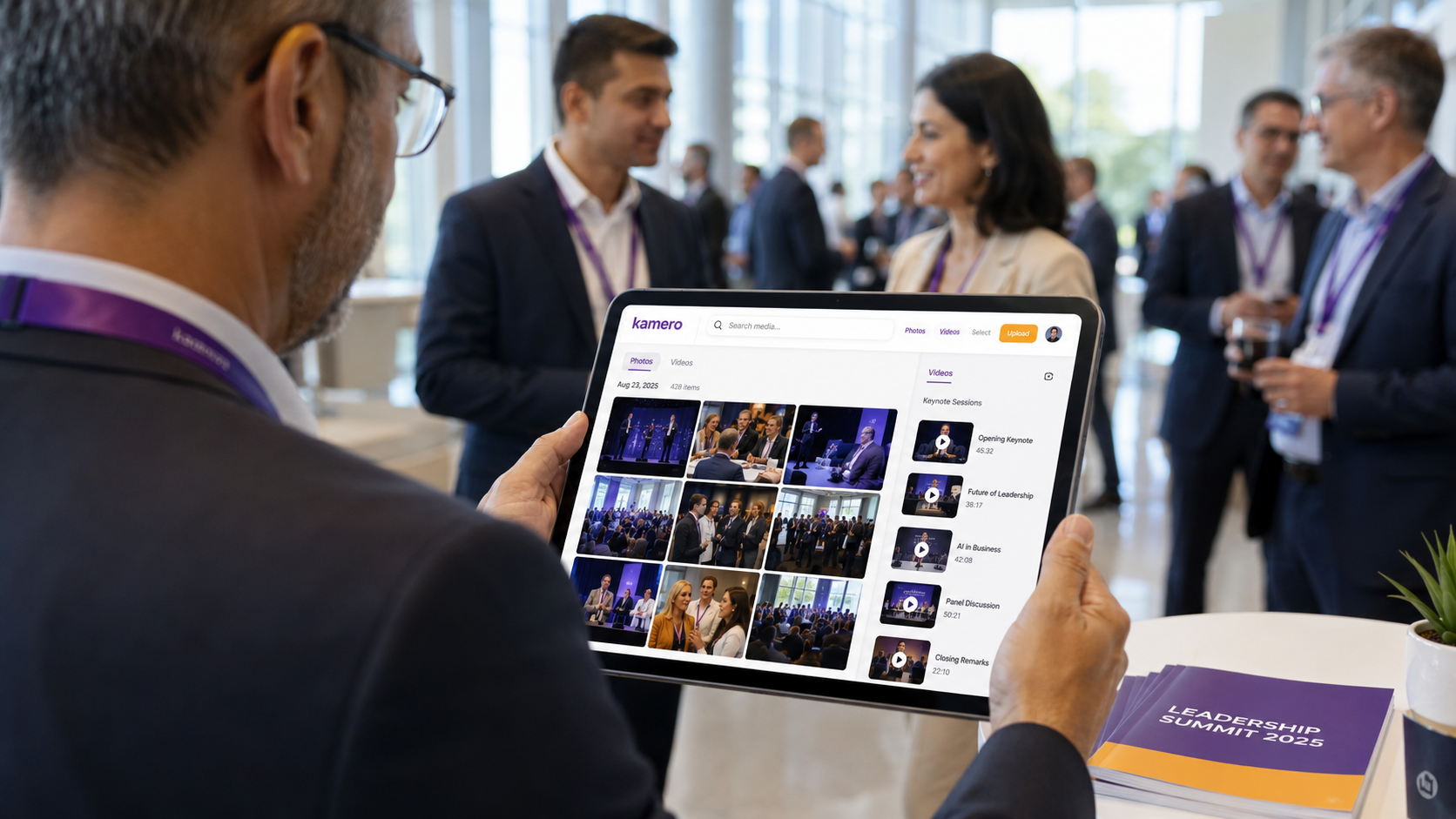 Event photographer capturing a corporate keynote while a marketing manager reviews newly uploaded event photos in real time on a tablet using an automated media delivery platform.