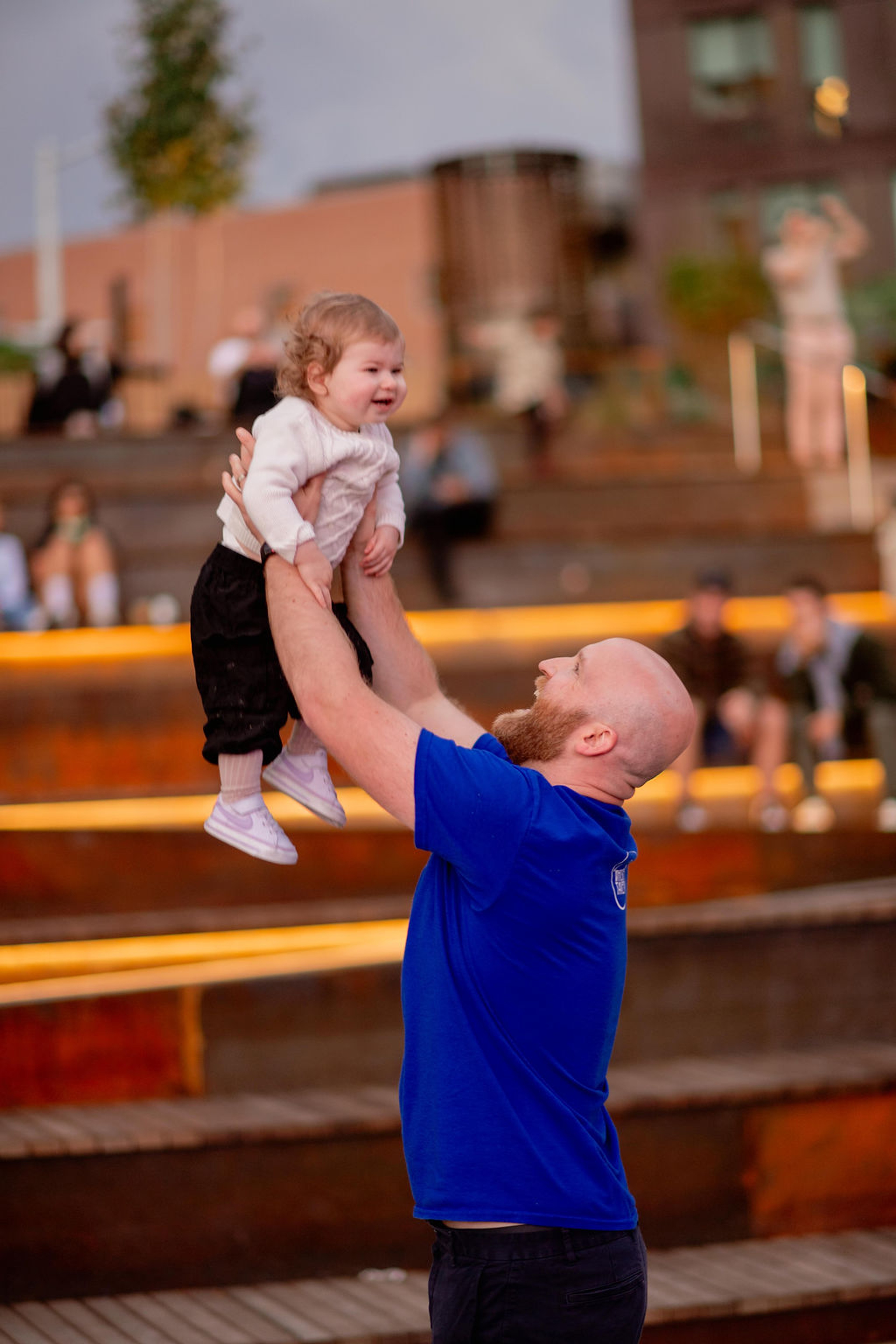 Caregiver lifting young child into the air