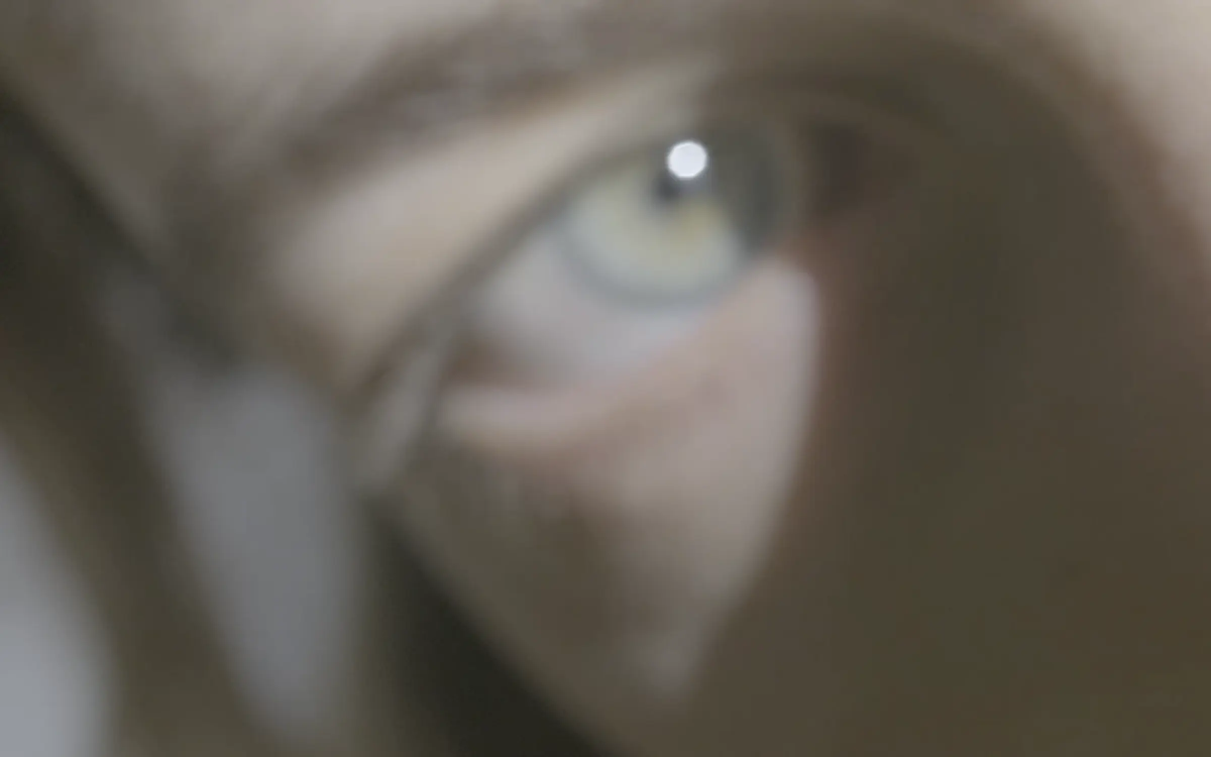 Blurry close up of sage green eye. Shadows casting across under eye.