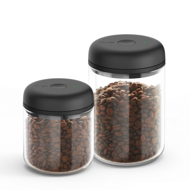 Fellow Atmos Vacuum Canister with black lid, filled with coffee beans on a white background.