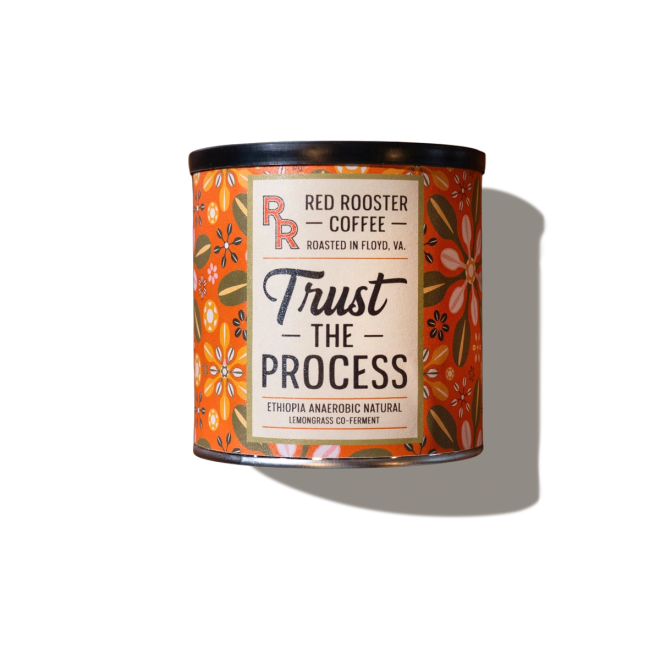 Orange Red Rooster Coffee tin with floral accents and a bold “Trust the Process” label, isolated against white.