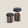 Fellow Atmos Vacuum Canister with black lid, filled with coffee beans on a white background.