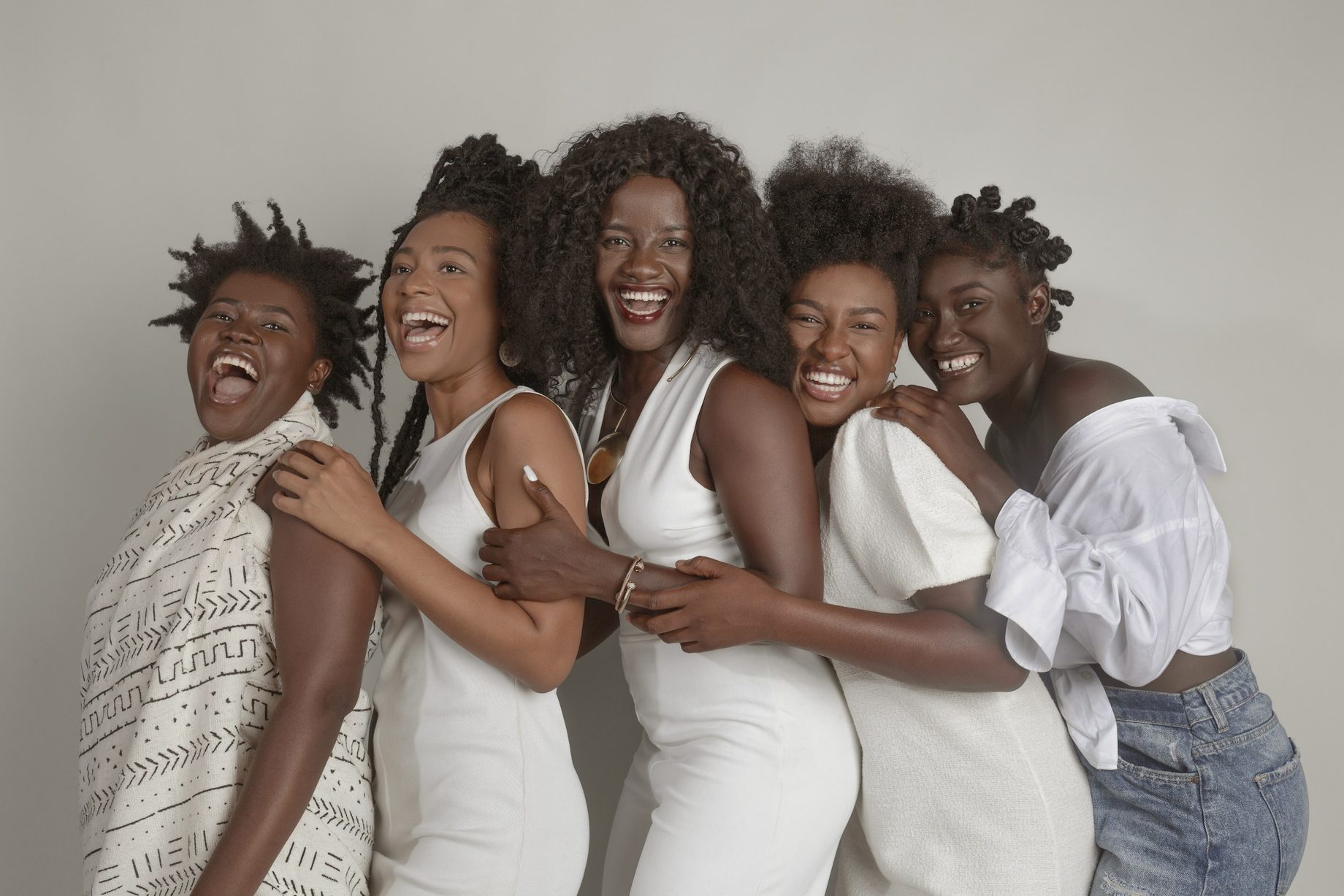 A group of women laughing together, arms around each other