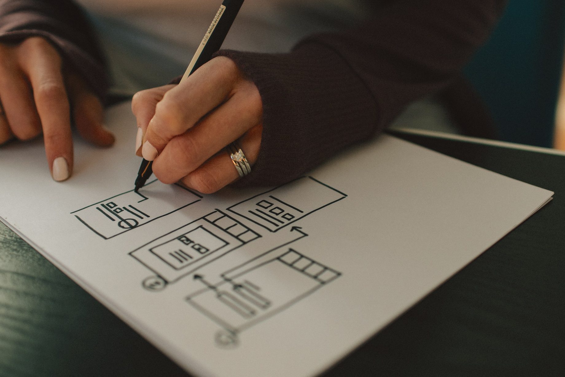 A hand sketching layout wireframes on paper