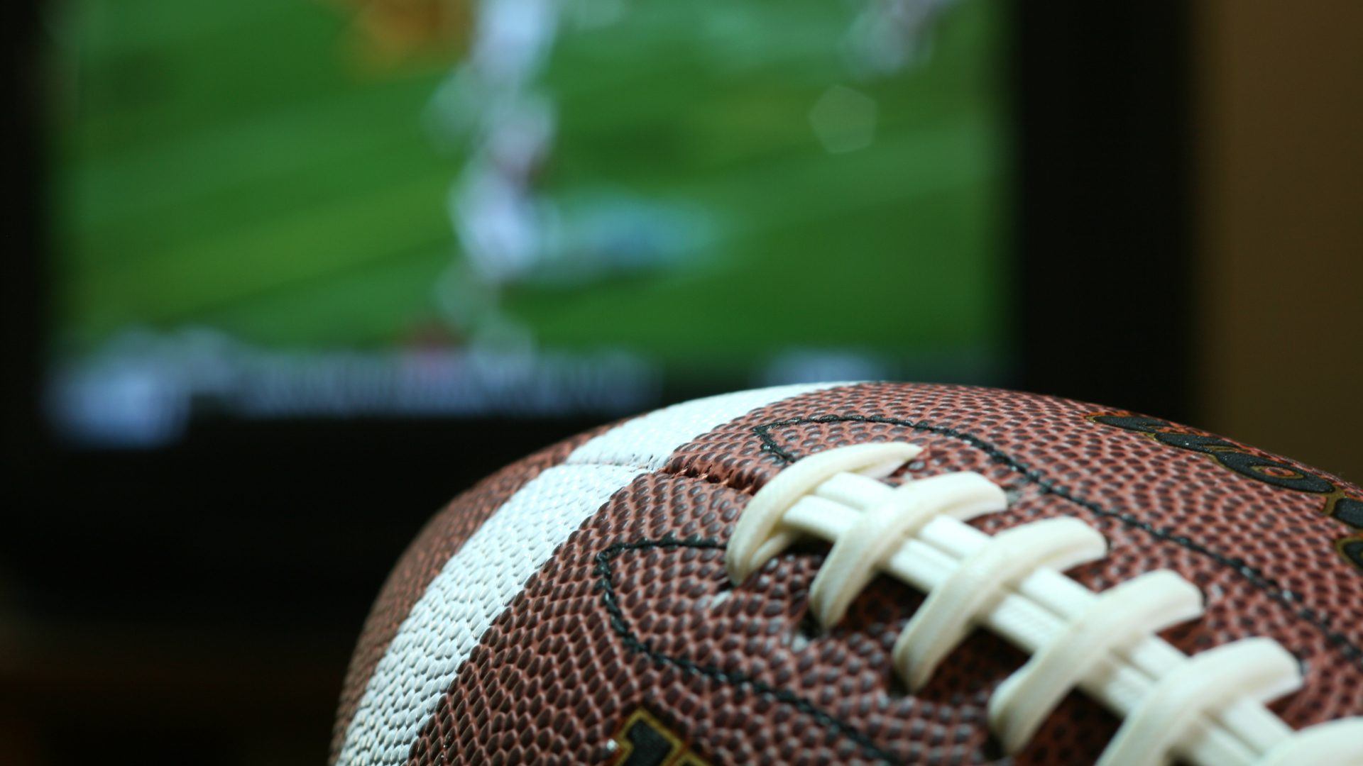 American football with TV blurred in the background.
