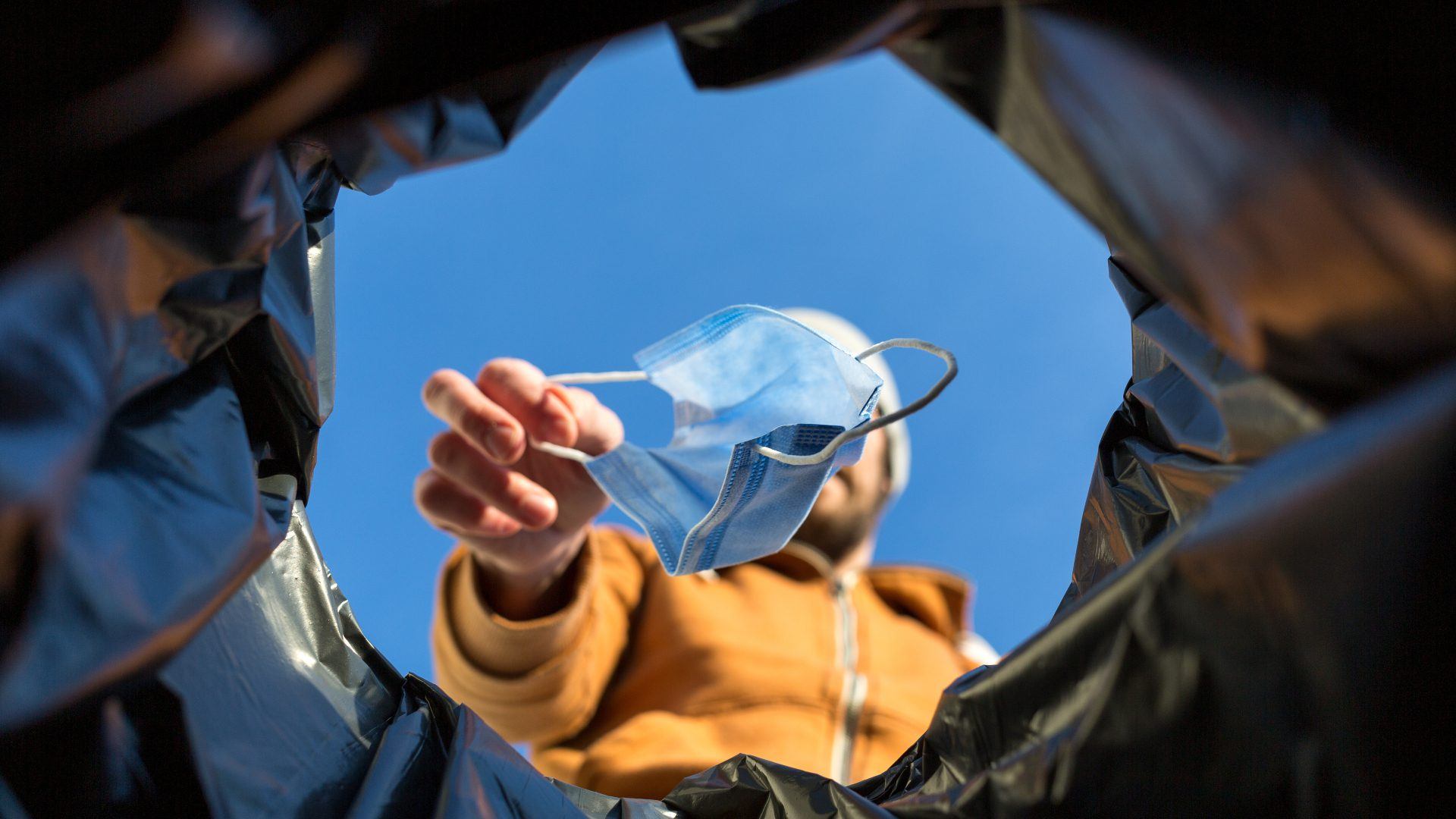 Point of view shot of man throwing away surgical mask in trash can