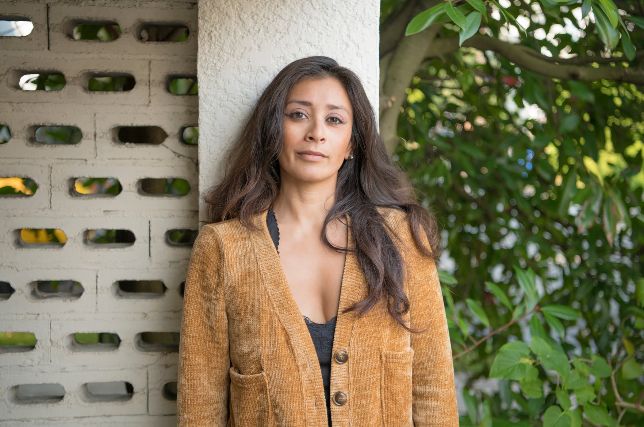 A person staring into the camera while leaning against a wall. 