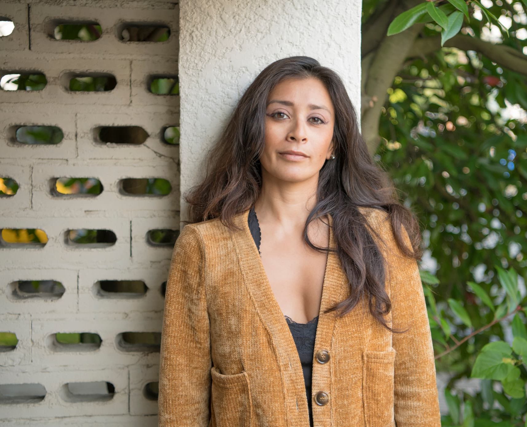 A person staring into the camera while leaning against a wall.