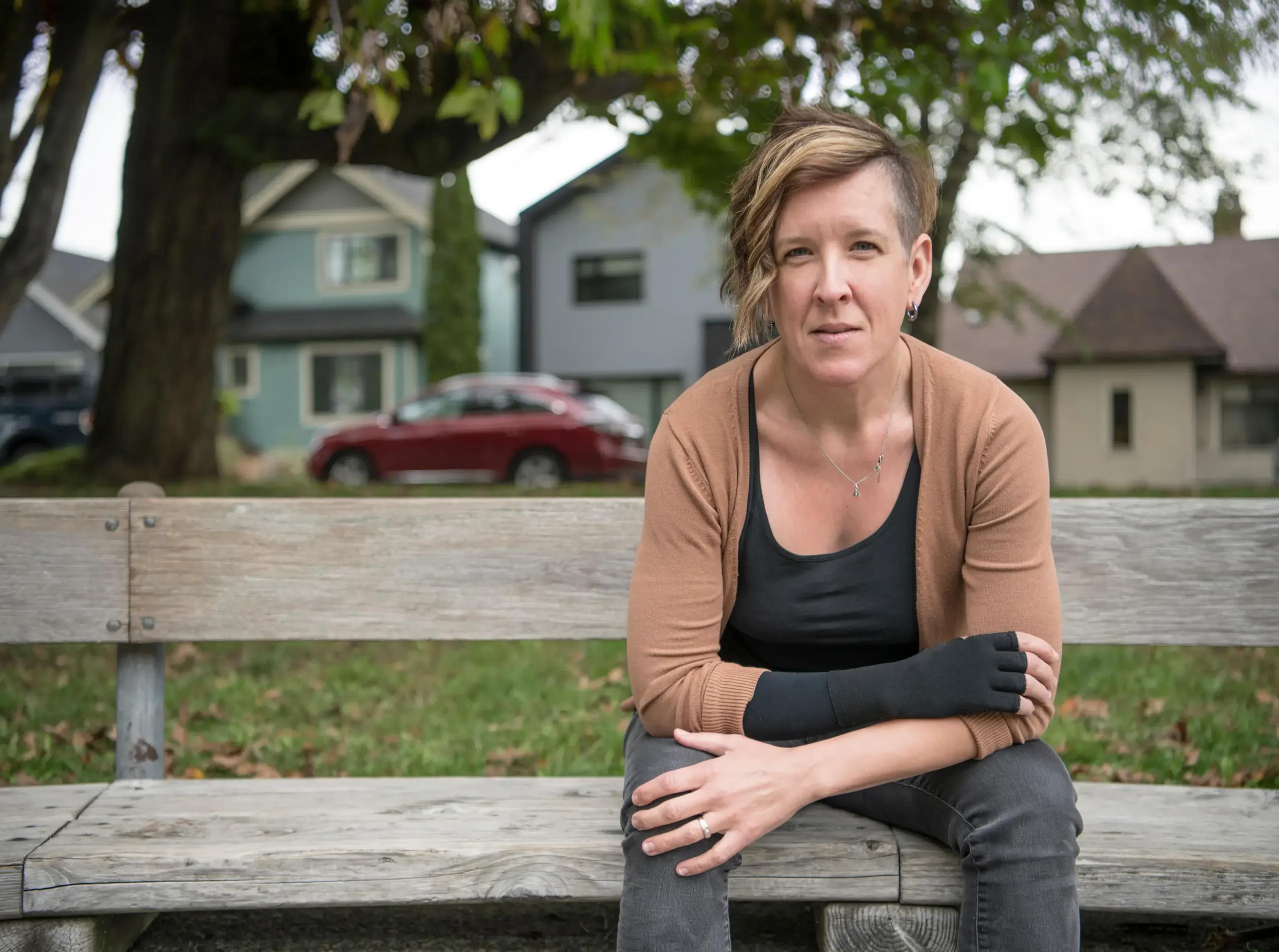 A person sitting outdoors wearing a wrist support.