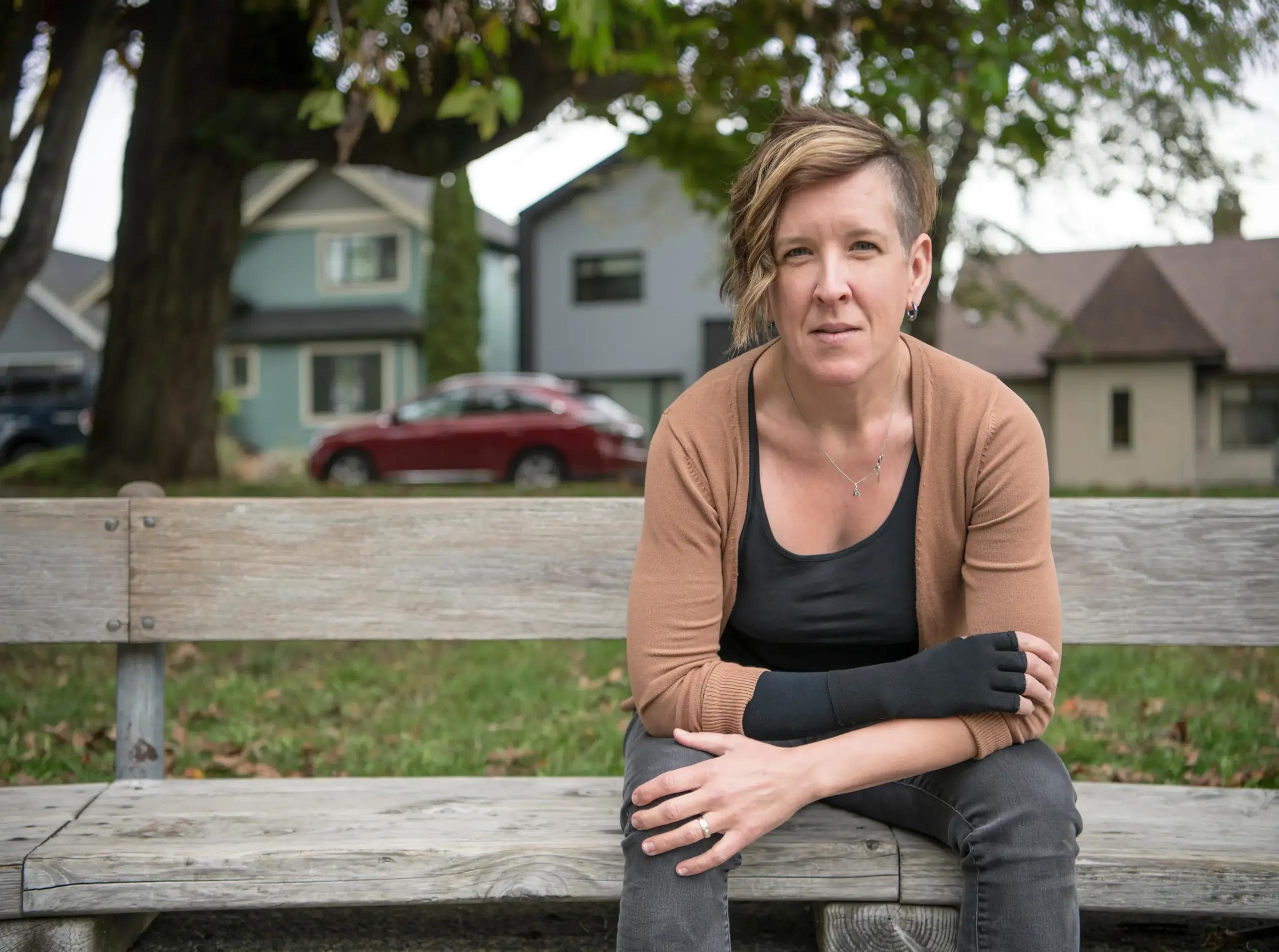 A person sitting outdoors wearing a wrist support.