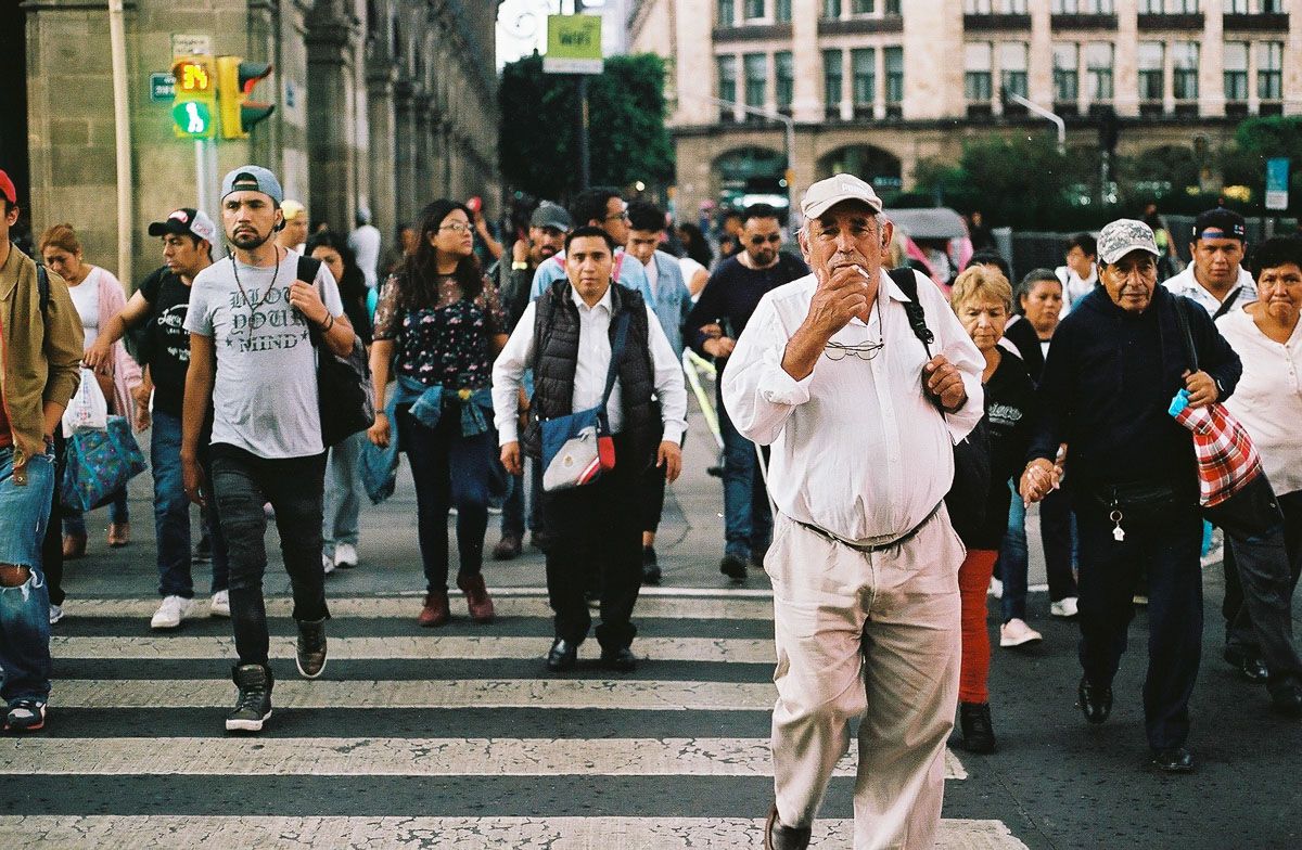Color analog street photograph of pedestrians crossing a busy Mexico City intersection.