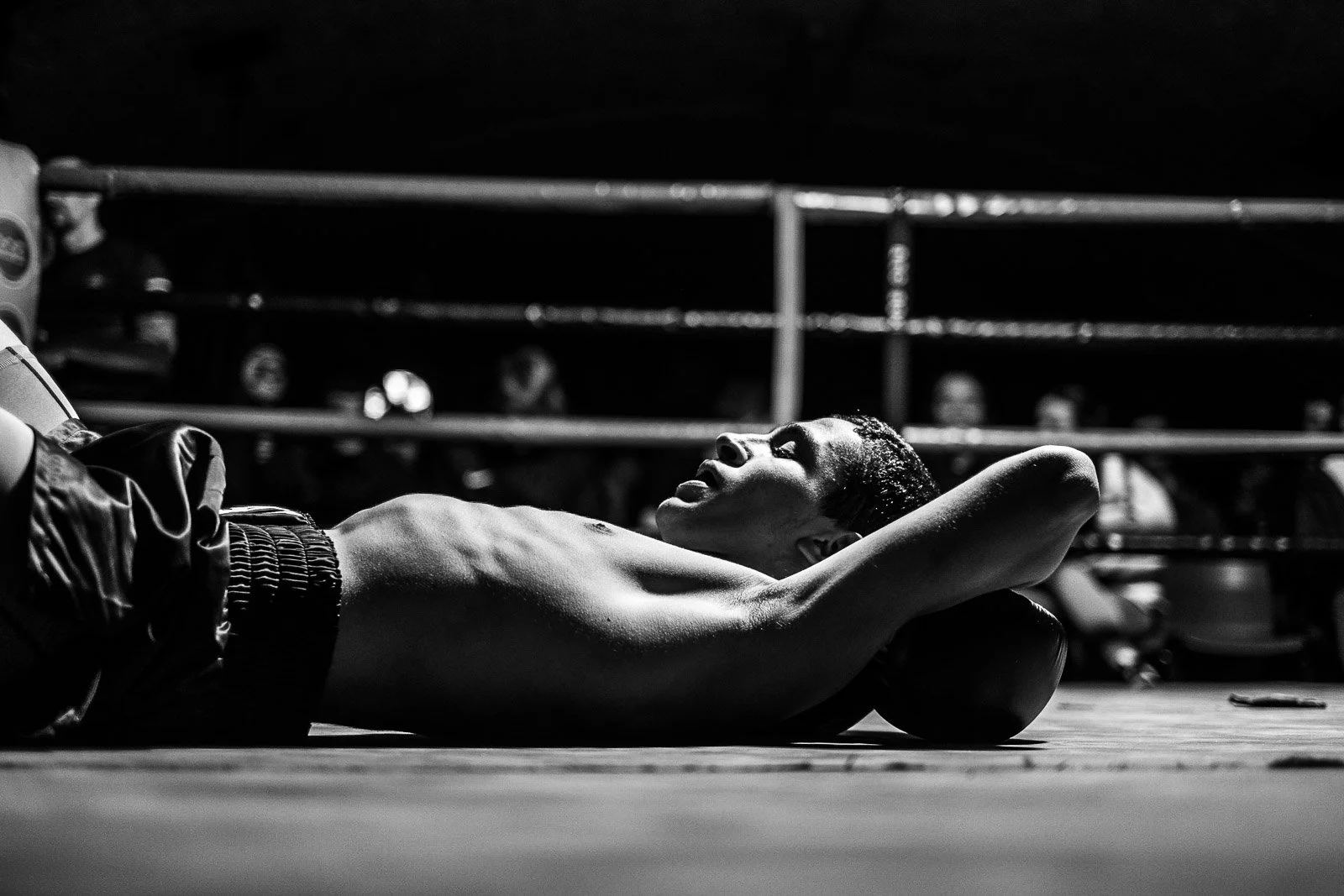 Exhausted Muay Thai fighter lies on the canvas after a bout