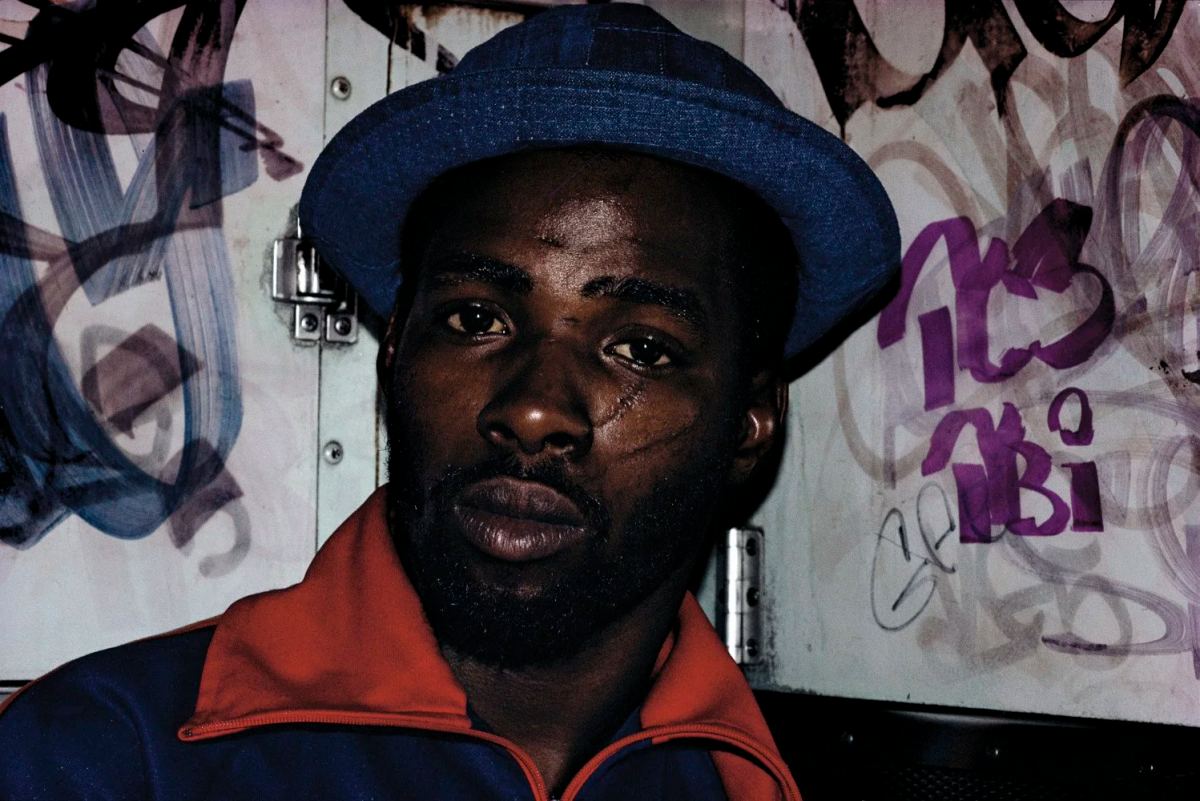 Bruce Davidson subway portrait of a man in a blue hat against a graffiti-covered wall