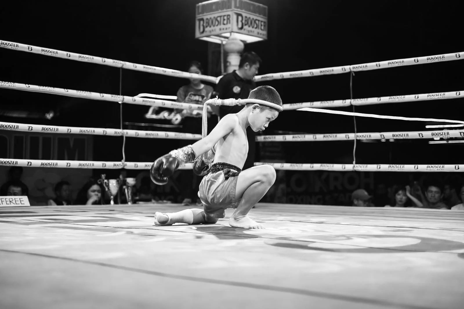 Young Muay Thai fighter kneels alone on the canvas