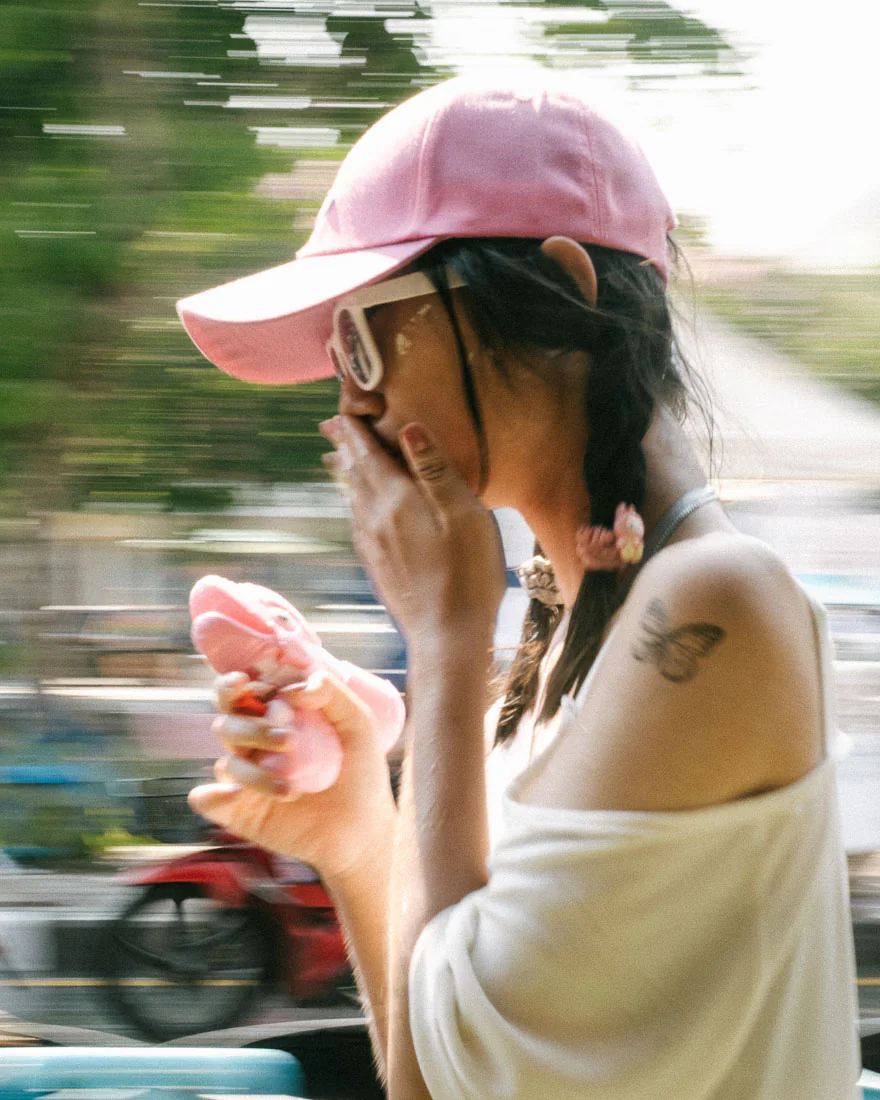 Woman in a pink cap shields her face while holding a pink water gun