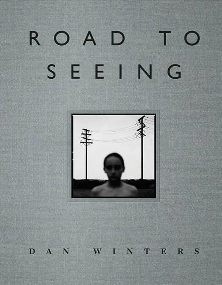 Book cover titled "Road to Seeing" by Dan Winters, featuring a blurred black and white photograph of a person with power lines in the background.