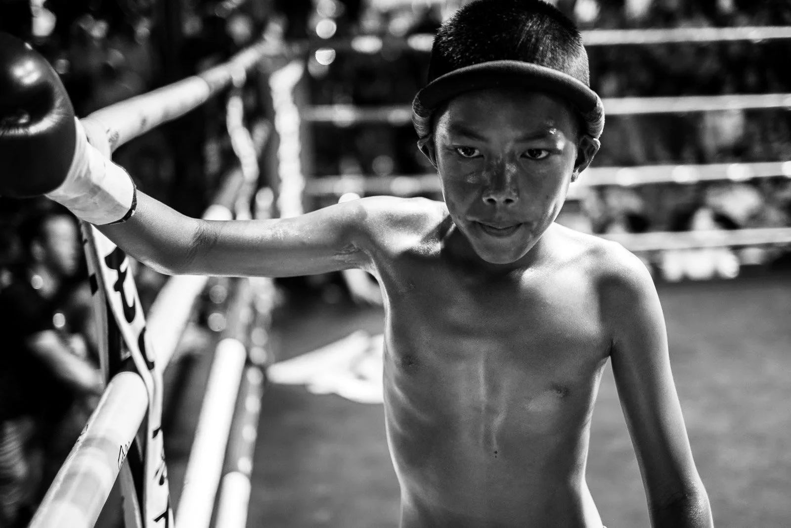 Young Muay Thai fighter rests one arm on the ring ropes