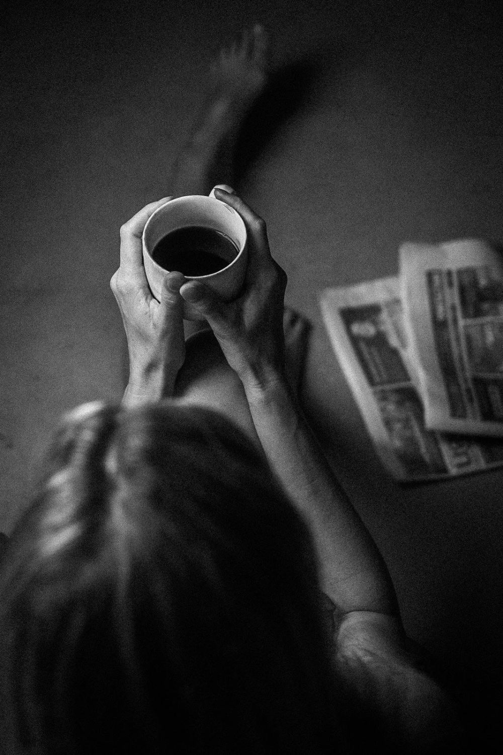 Overhead black-and-white photograph of a woman holding up a cup