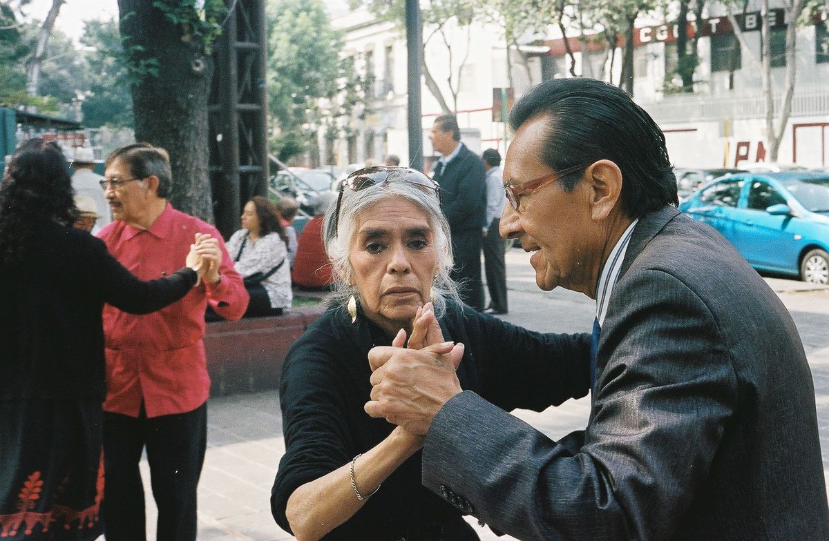 Color analog street photograph of an older couple dancing in Mexico City.