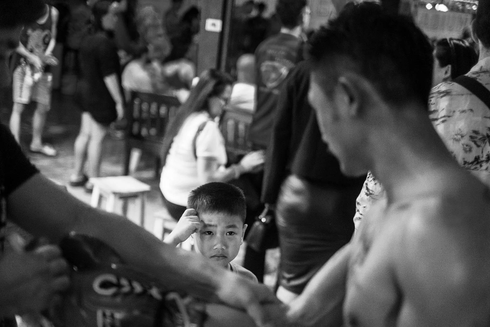 Young boy watches his father beside a Muay Thai ring
