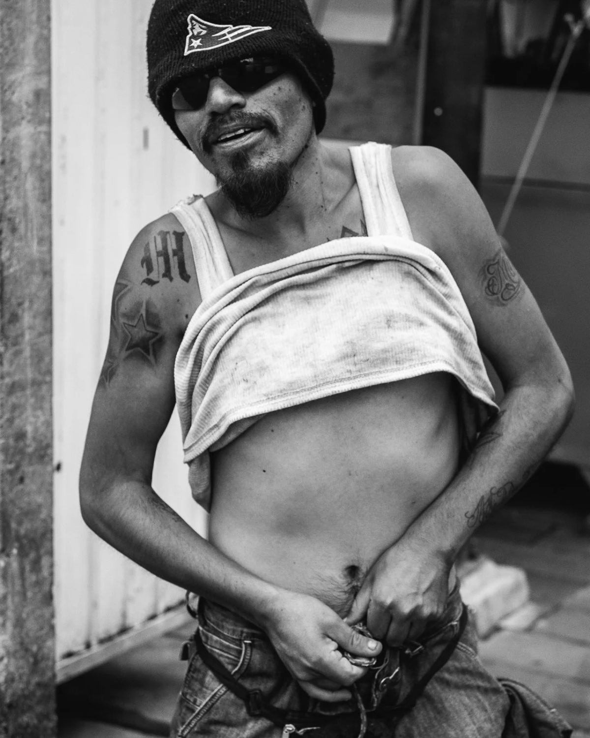Black-and-white street portrait of a man in a cap with his shirt rolled up