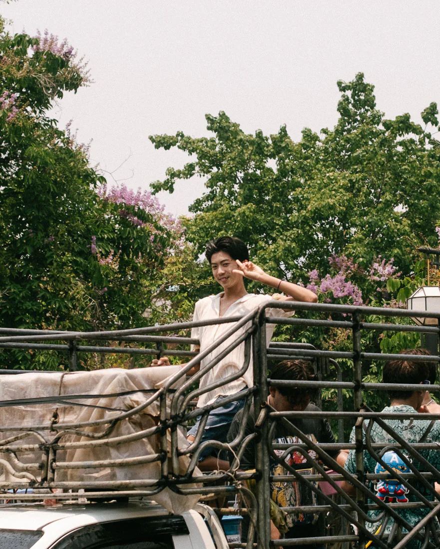 Young man flashes a peace sign from the back of a Songkran pickup truck