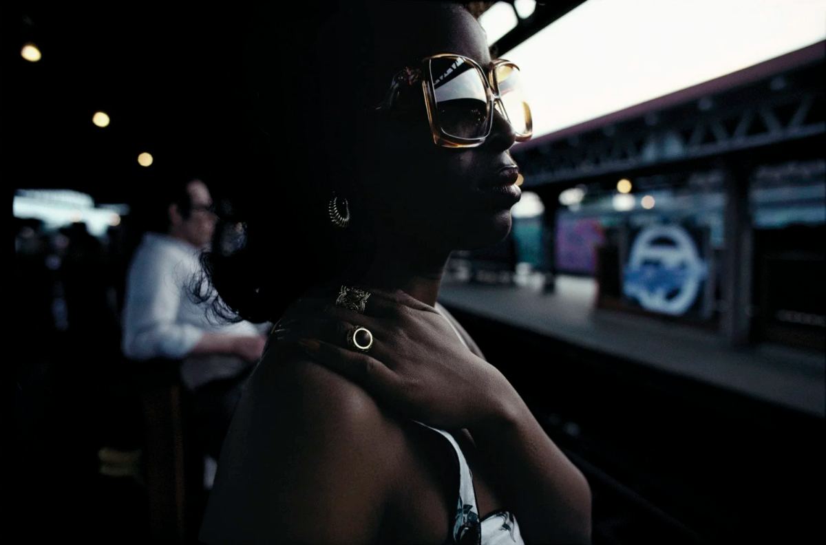 Bruce Davidson photograph of a woman wearing large sunglasses beside a subway train