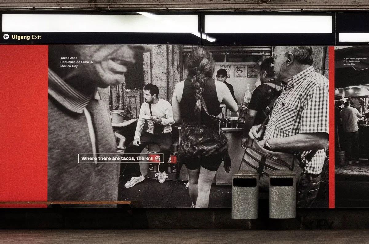 Coca-Cola taco-stand photograph displayed on a subway station advertising wall