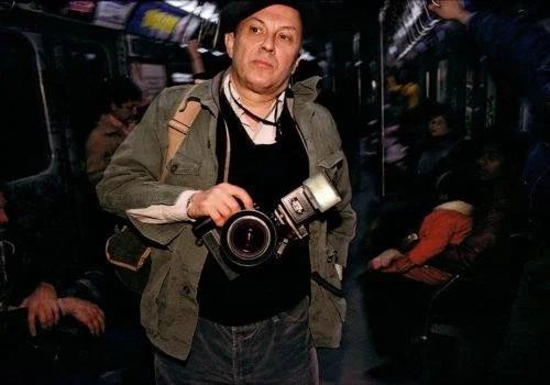 Bruce Davidson holding a camera and flash inside a subway carriage