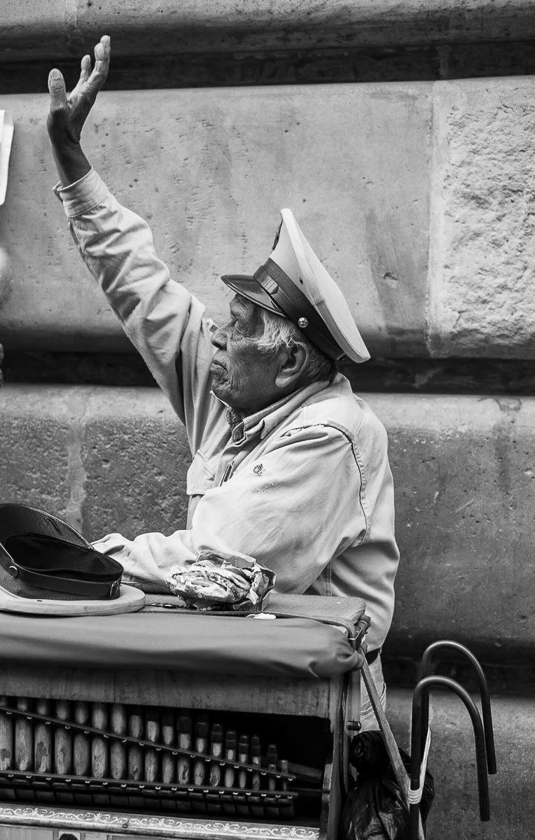 Black-and-white photograph of a uniformed man raising his hand from an open vehicle