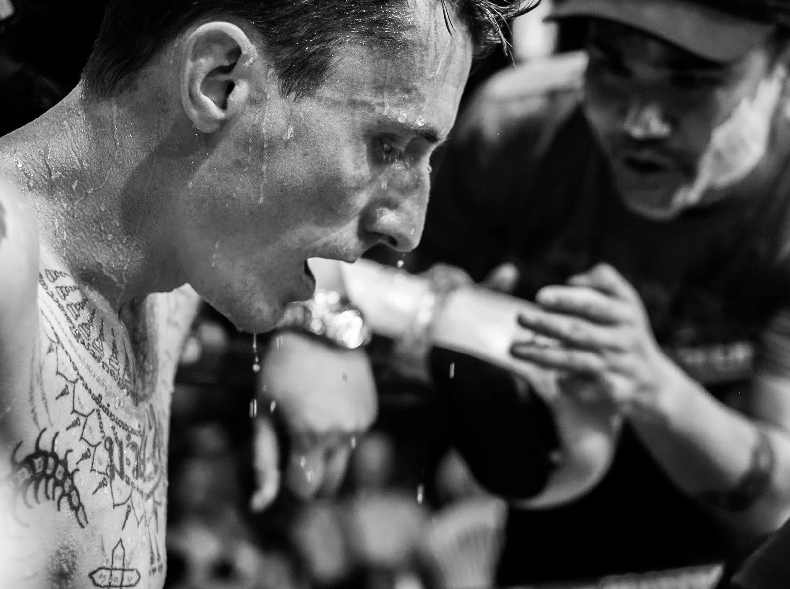 Sweating Muay Thai fighter listens to his corner between rounds