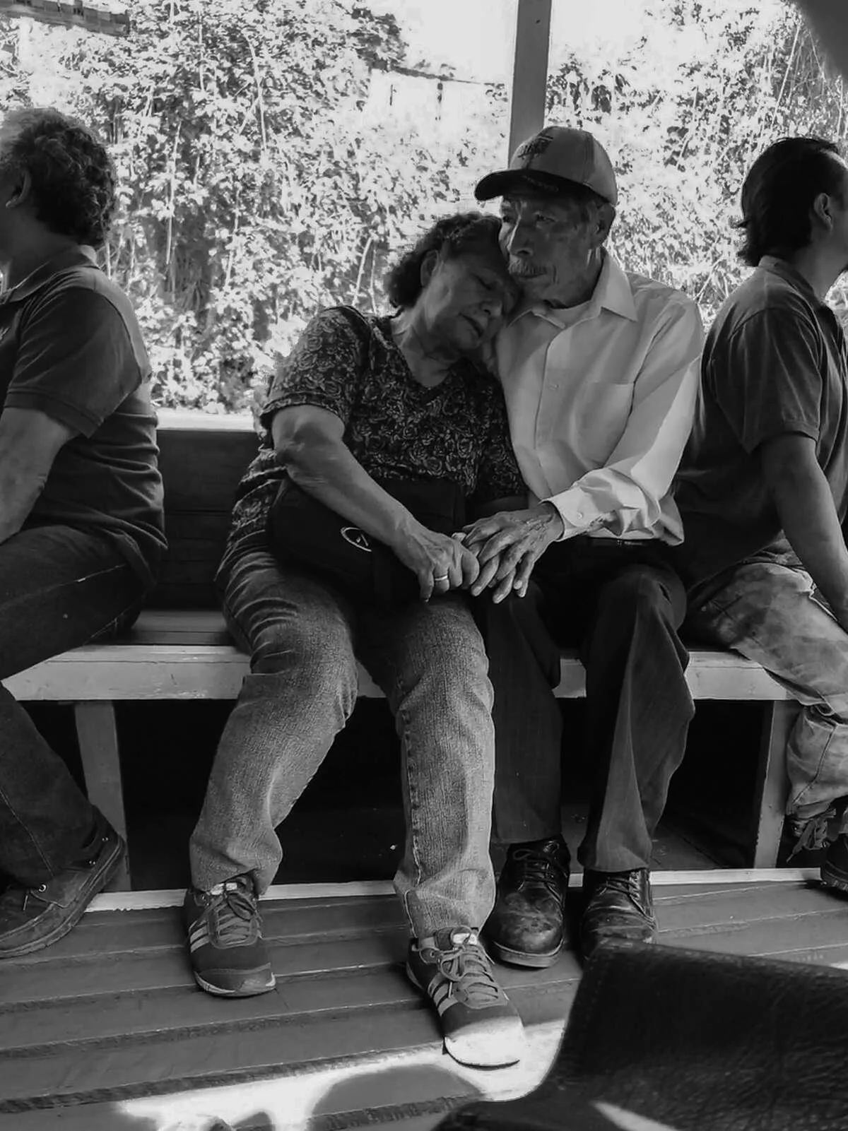 Black-and-white Mexico City street photograph of a couple embracing on a park bench