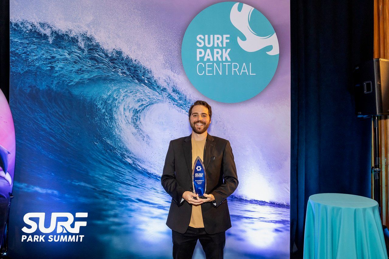 Cash Lambert holding his award in front of the Surf Park Central backdrop at the Surf Park Summit
