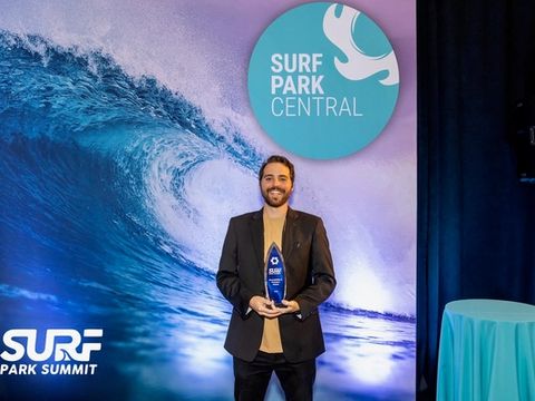 Cash Lambert holding his award in front of the Surf Park Central backdrop at the Surf Park Summit