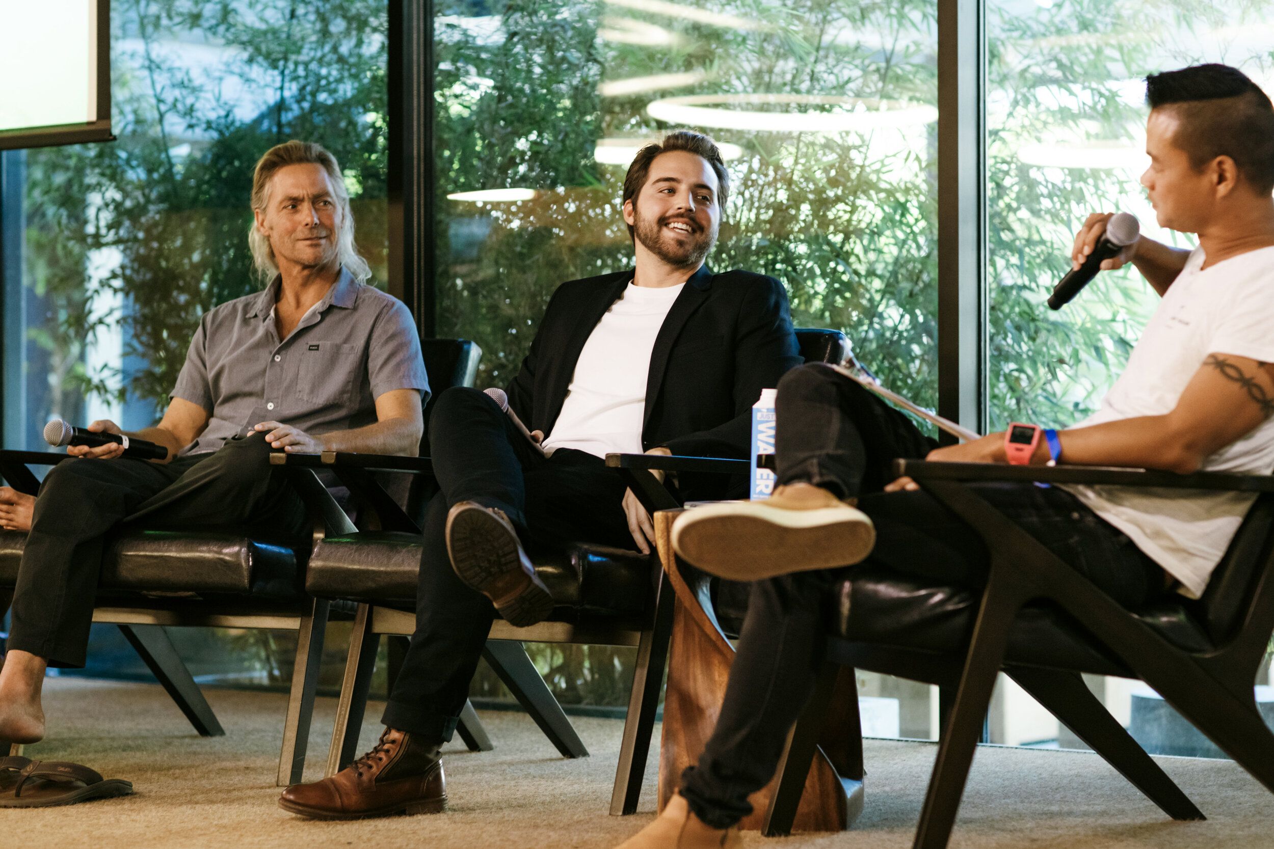 Cash Lambert speaking into a microphone alongside three other panelists on stage