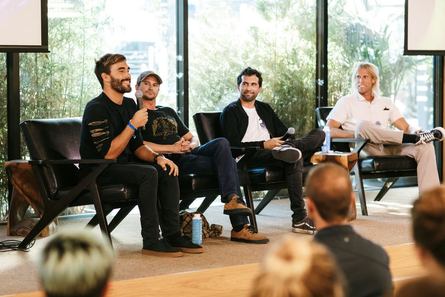 Cash Lambert speaking into a microphone alongside three other panelists on stage