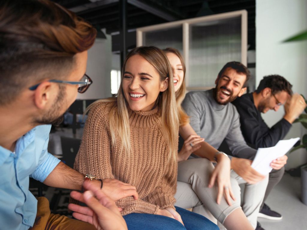 two men and three women sitting in an open plan office and having a meeting