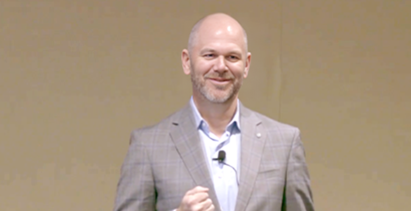 photo of a man in a suit with a mic attached to his shirt