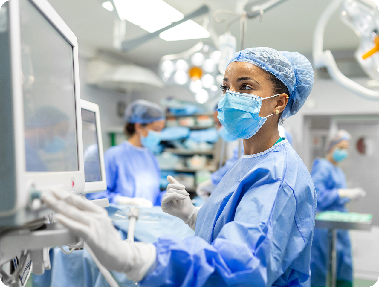 Surgeon in protective equipment looking at a screen