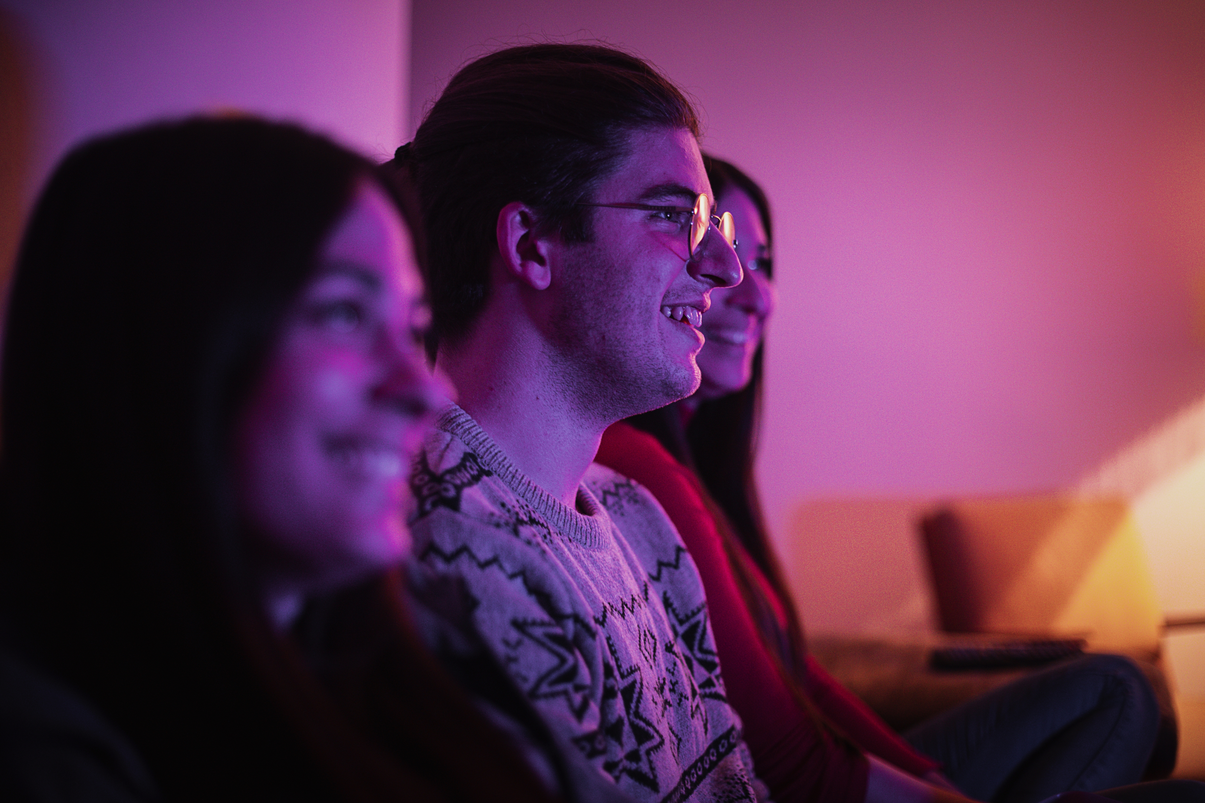 Philips customer story image - Several people in colored lighting watching a TV