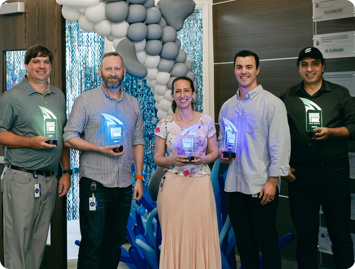 SailPoint employees holding illuminated shark fin awards at a company event