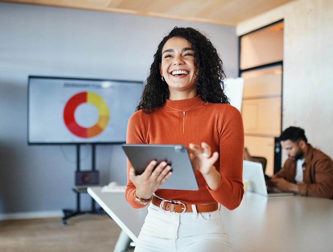 Professional holding a tablet in an office with an identity security chart behind her