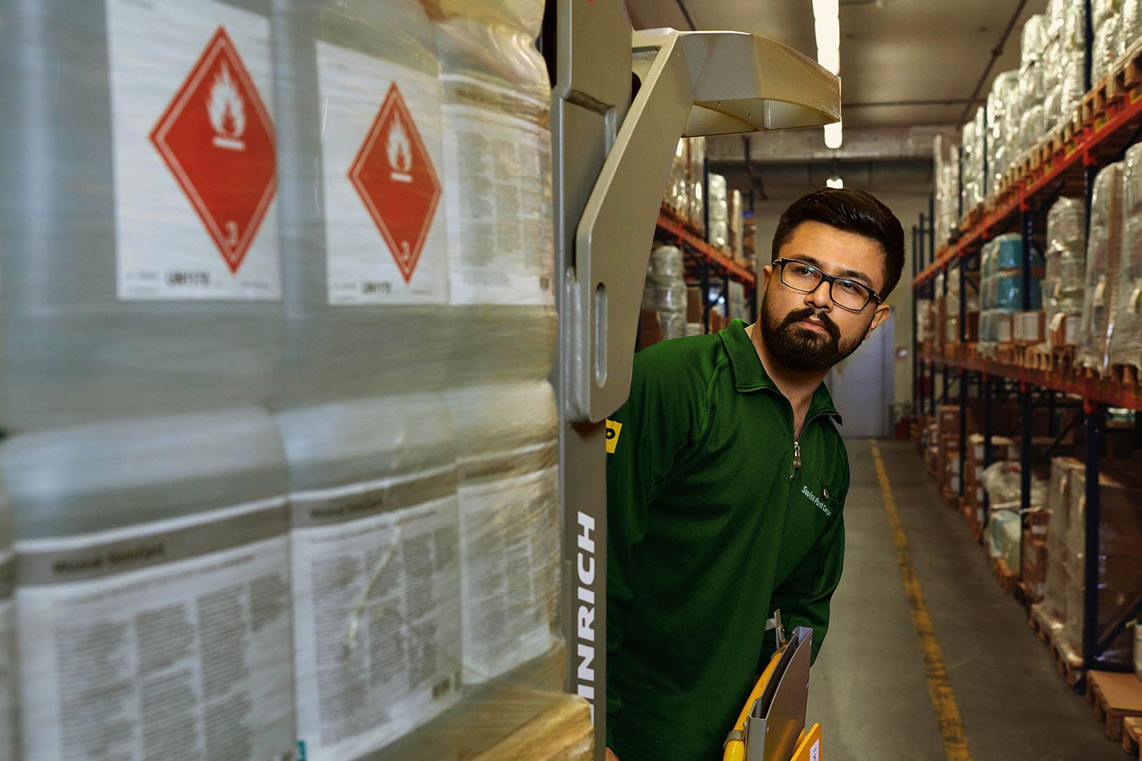 A warehouse worker transports hazardous goods on a pallet jack in the hazardous materials warehouse.