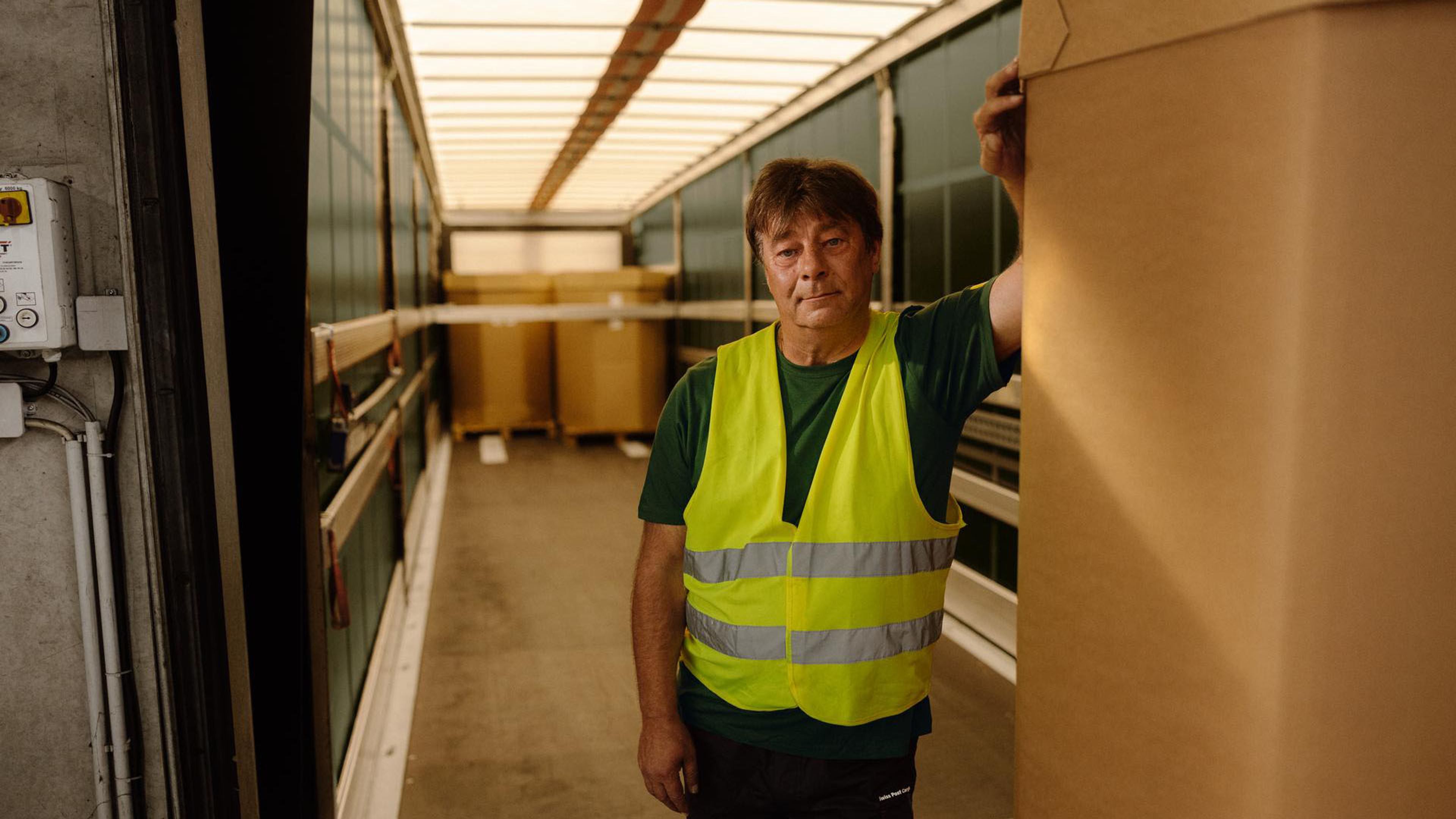 Il collaboratore di Swiss Post Cargo si appoggia su una superficie di carico per autocarri.