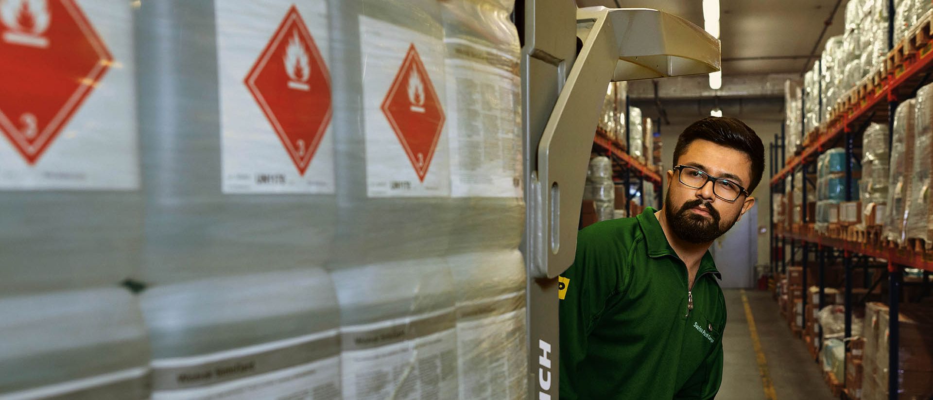 A warehouse worker transports hazardous goods on a pallet jack in the hazardous materials warehouse.