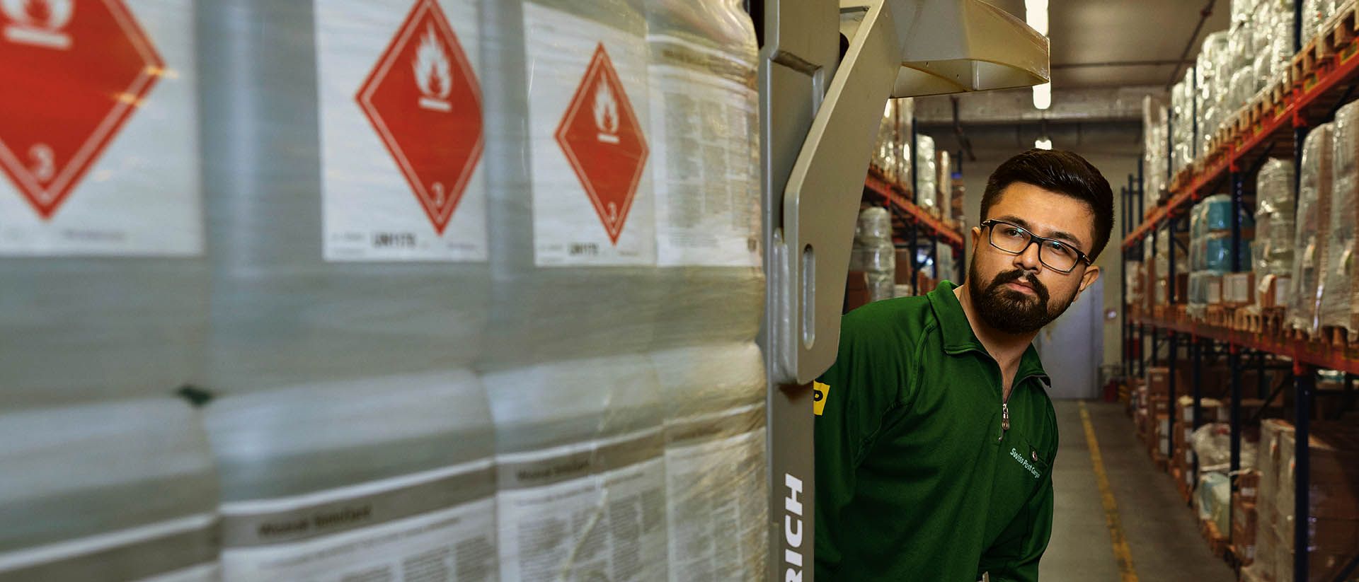 Ein Lagerarbeiter transportiert Gefahrgut auf einem Hubwagen im Gefahrstoff-Lager.