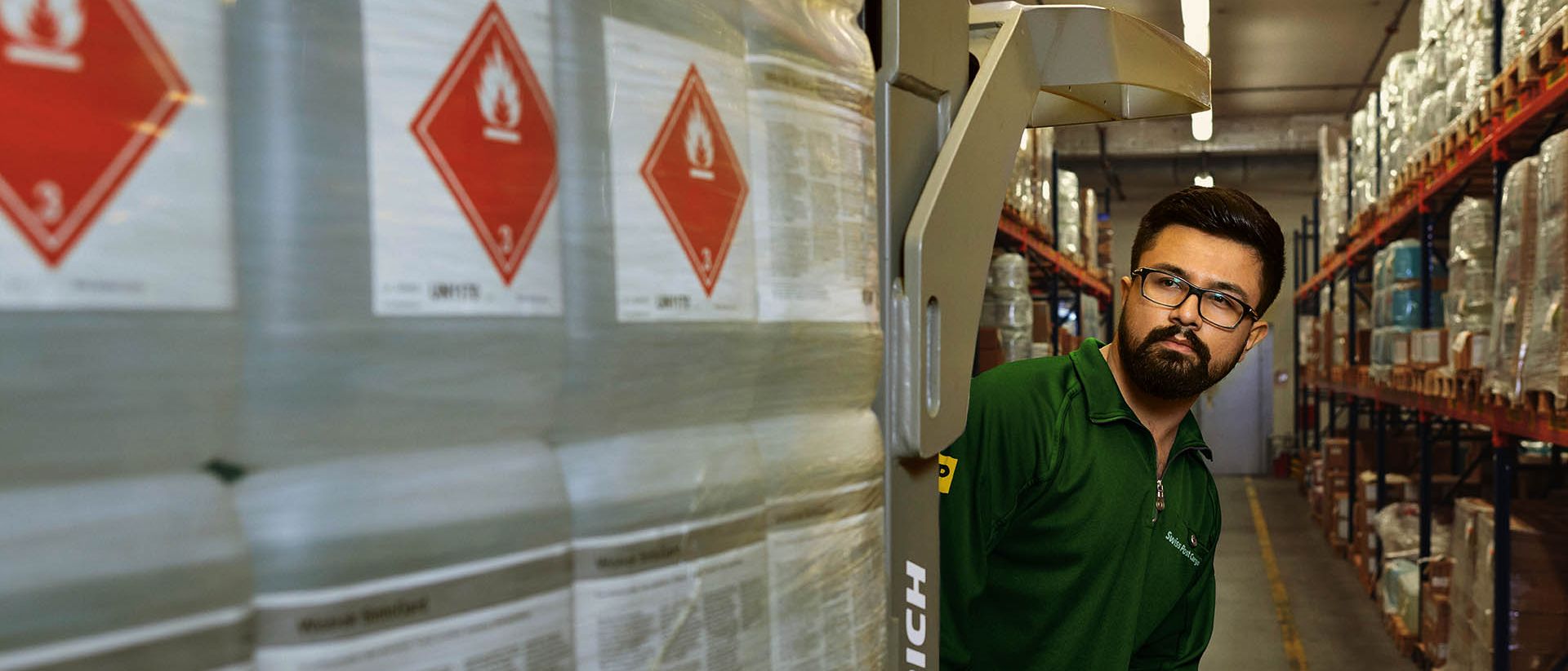 A warehouse worker transports hazardous goods on a pallet jack in the hazardous materials warehouse.
